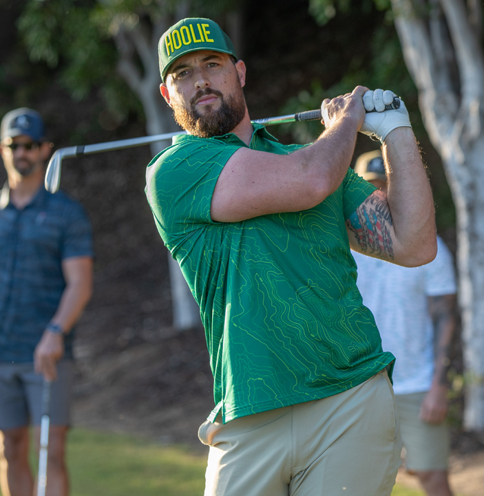 Golfer Swings Wearing Garden City Recce Men's Golf Polo in Green