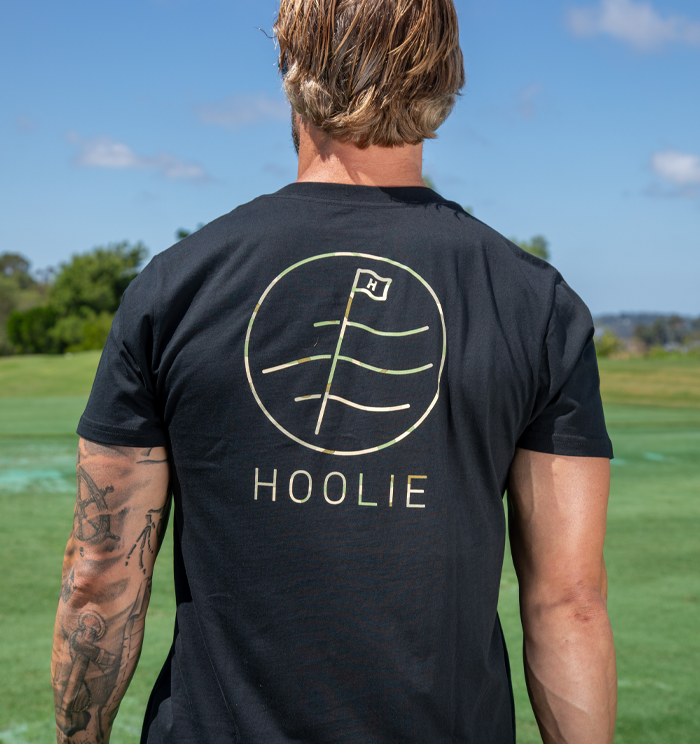 Golf T Shirt for Men in black with multicam flag logo, veteran-inspired detail, and Hoolie branding.