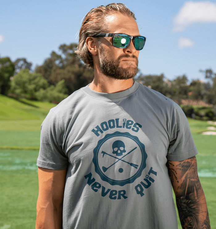 Men's Hoolie's Never Quit Golf T Shirt with skull-and-crossbones badge graphic.