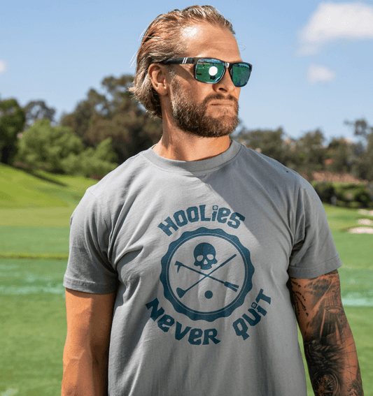 Men's Hoolie's Never Quit Golf T Shirt with skull-and-crossbones badge graphic.