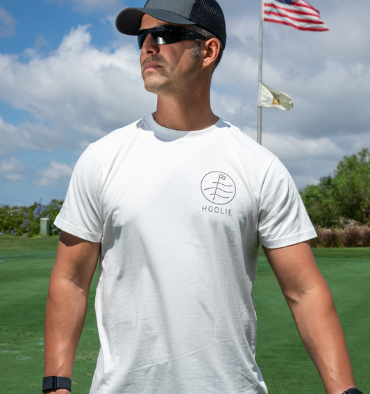 Men's White Hoolie Flag Badge Golf T Shirt with black and white front badge and colorful golf course back design.