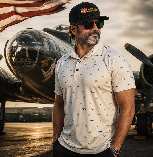 Model in front of a WWII plane wearing a Bombers Men's Golf Polo and Dawn's Early Light Rope hat as part of Bombers Bundle