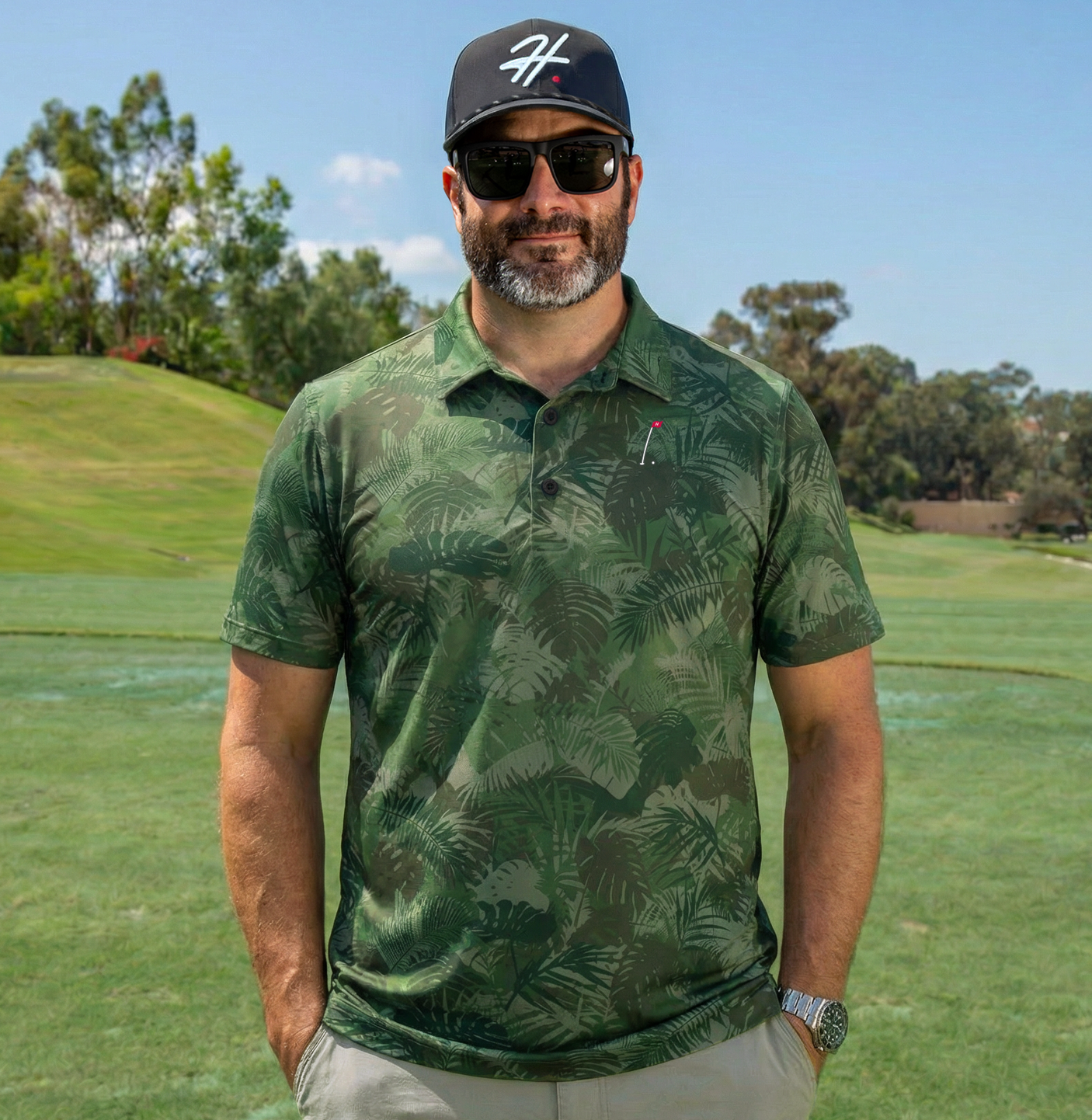 Man Wearing Men's Performance Golf Polo with Various Shades of Green Jungle Palm Fronds