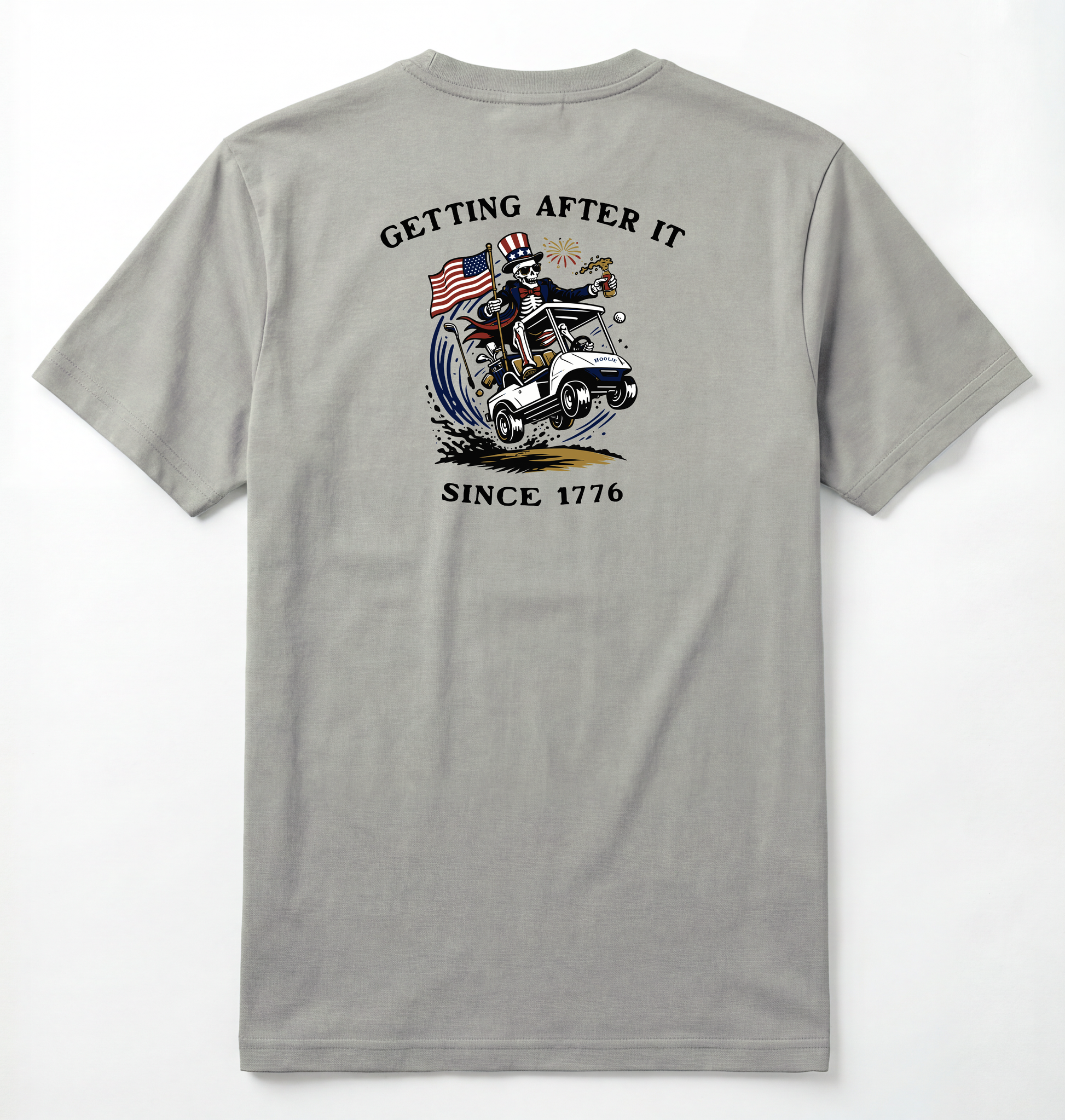 Back of Light gray T-shirt with Uncle Sam Skeleton Character in a Golf Cart carrying an American Flag with Text surrounding that says Getting After it Since 1776