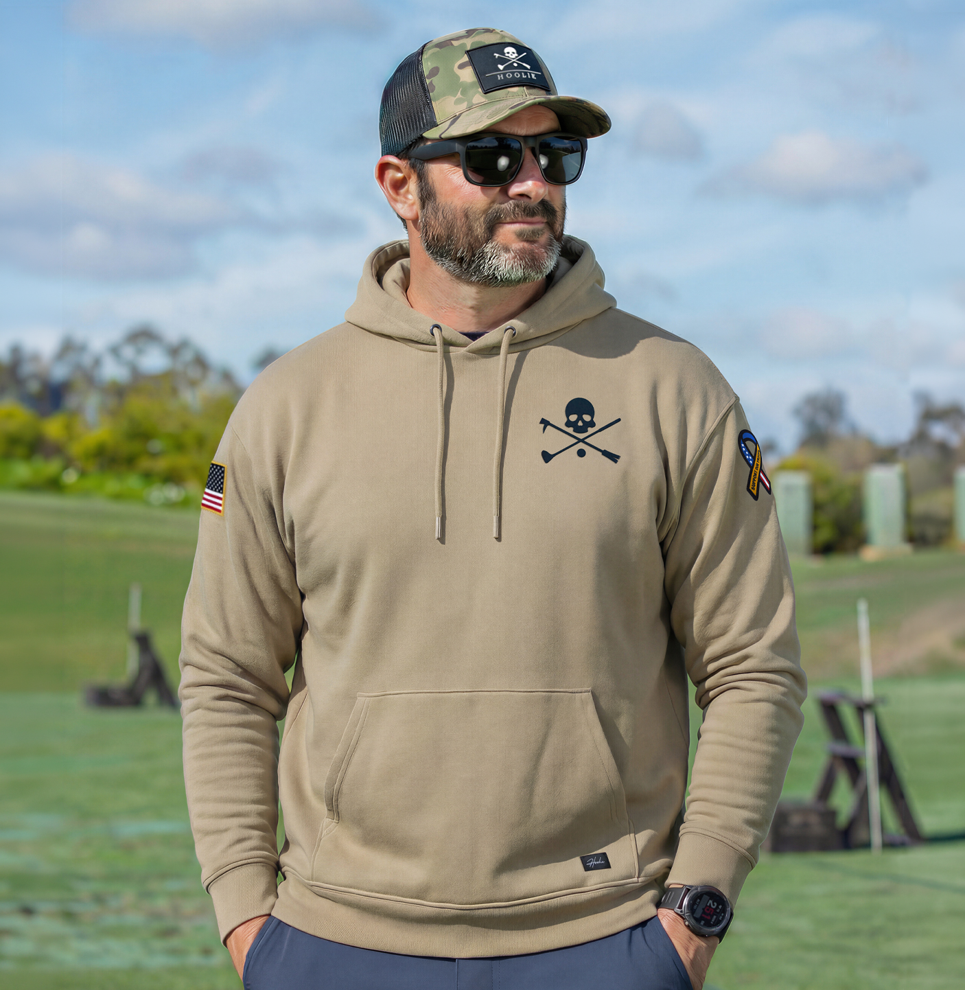 Man wearing a Coyote Tan hoodie with Hoolie X Bones patch, an American Flag and a Support our Troops patch. Limited Edition Hoodie.